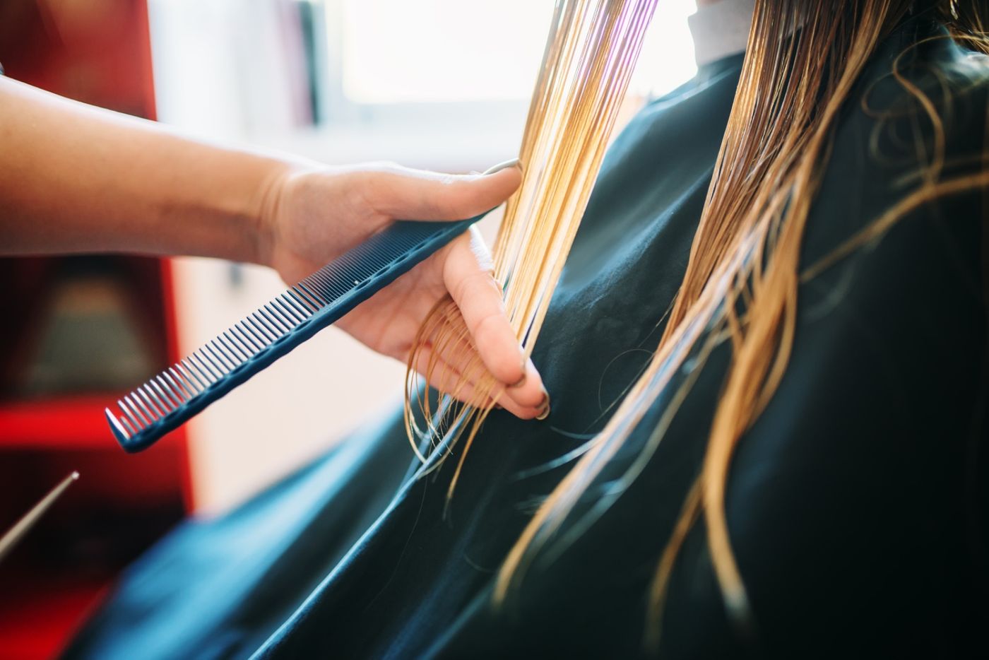 Coiffeuse peignant une longue chevelure en salon