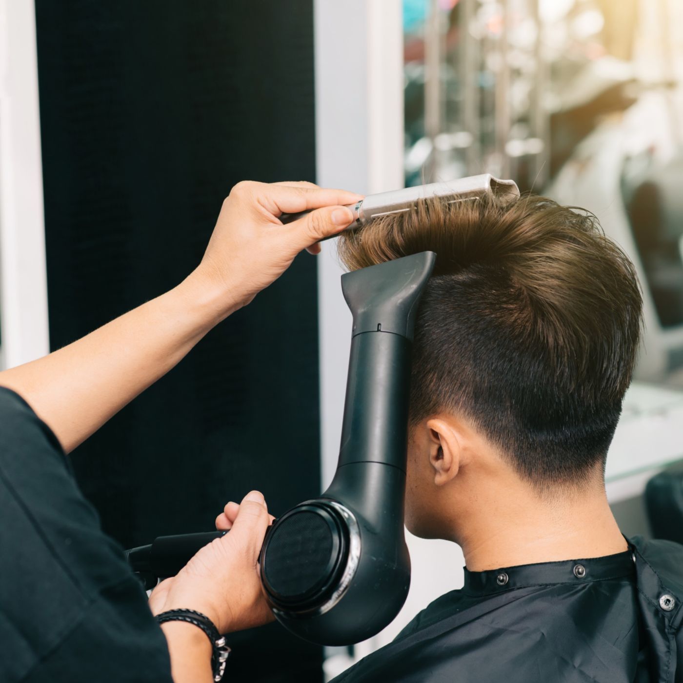 Coiffeur réalisant un brushing masculin en salon professionnel